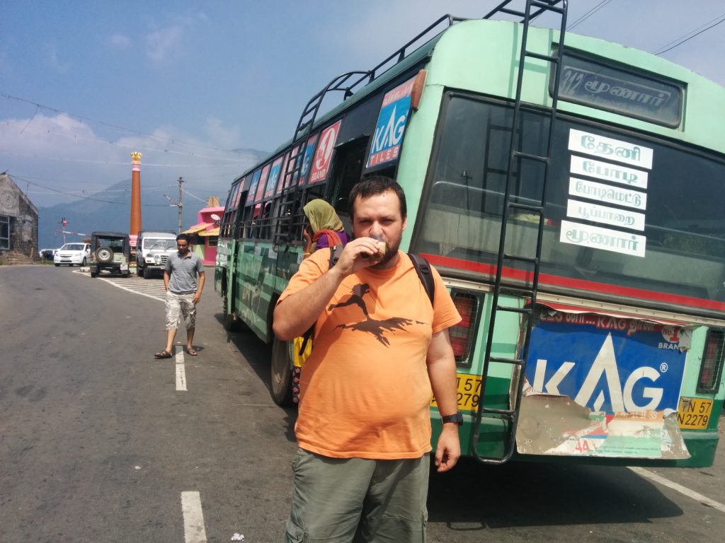 Homem a beber Massala Tea ao pé de autocaro na fronteira entre Tamil Nadu e Kerala